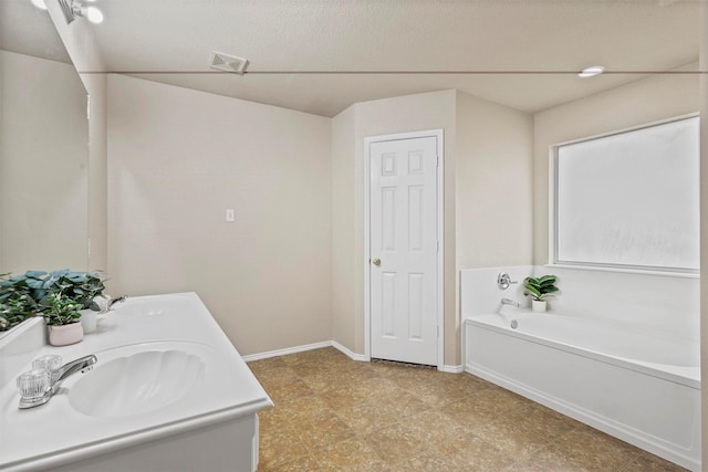 bathroom with a garden tub, a sink, visible vents, and double vanity