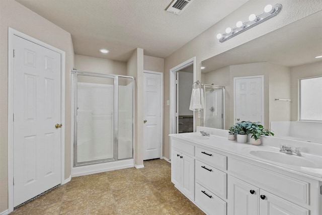 bathroom featuring double vanity, a stall shower, a sink, and visible vents