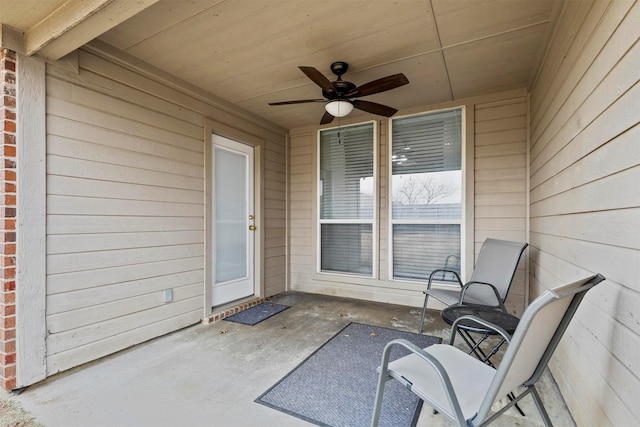 doorway to property featuring brick siding, a patio area, and a ceiling fan