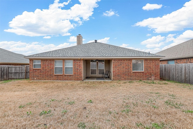 back of house featuring a yard, brick siding, and a fenced backyard