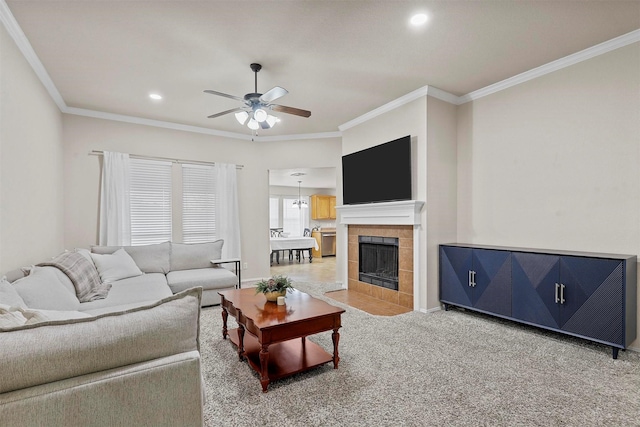 carpeted living room with crown molding, recessed lighting, ceiling fan, a tile fireplace, and baseboards