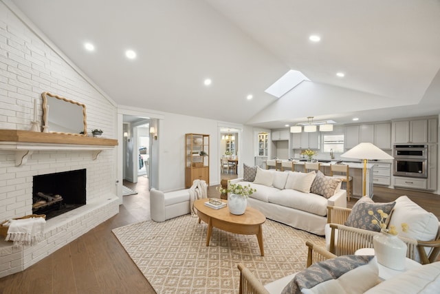 living room featuring lofted ceiling with skylight, a brick fireplace, wood finished floors, and recessed lighting