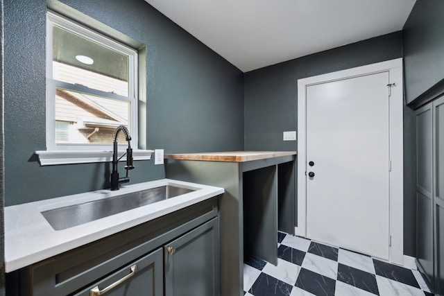 laundry room with a textured wall, a sink, and tile patterned floors