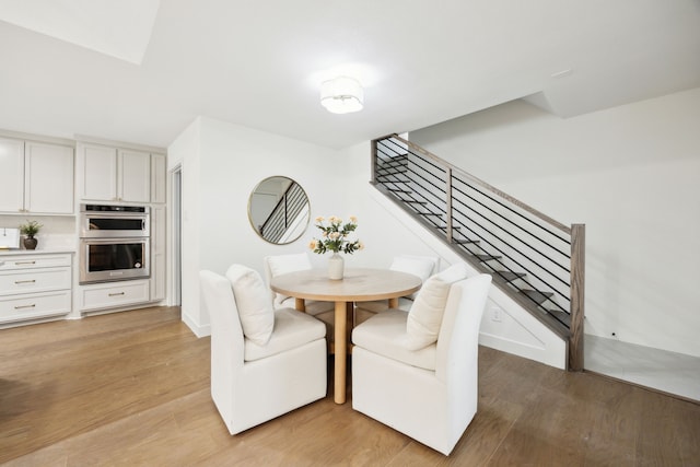 dining area featuring light wood-style flooring, stairs, and baseboards