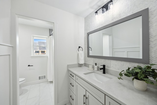 bathroom with toilet, vanity, visible vents, baseboards, and tasteful backsplash