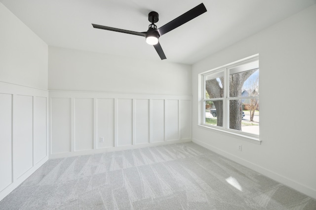 carpeted spare room featuring ceiling fan and a decorative wall