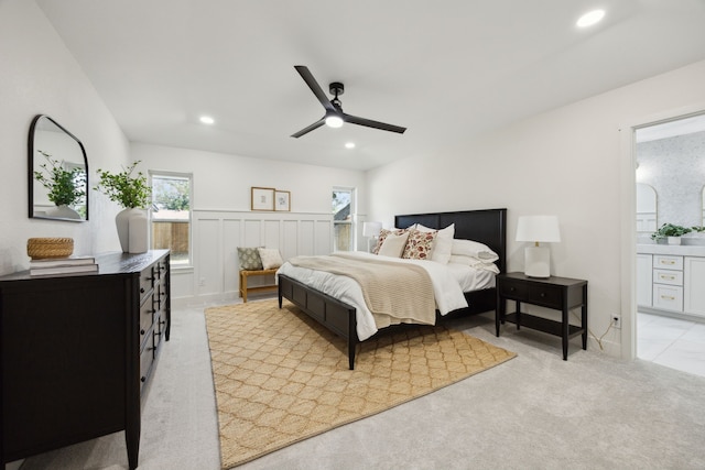 bedroom with connected bathroom, recessed lighting, a wainscoted wall, light colored carpet, and a ceiling fan