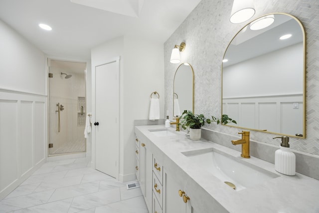 bathroom with marble finish floor, a wainscoted wall, a sink, and a stall shower