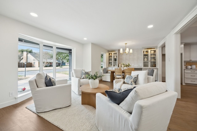 living area with baseboards, an inviting chandelier, wood finished floors, and recessed lighting