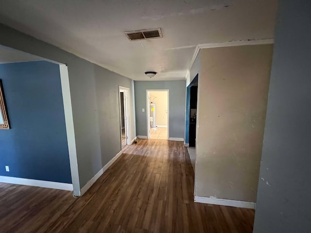 hall featuring visible vents, baseboards, and wood finished floors