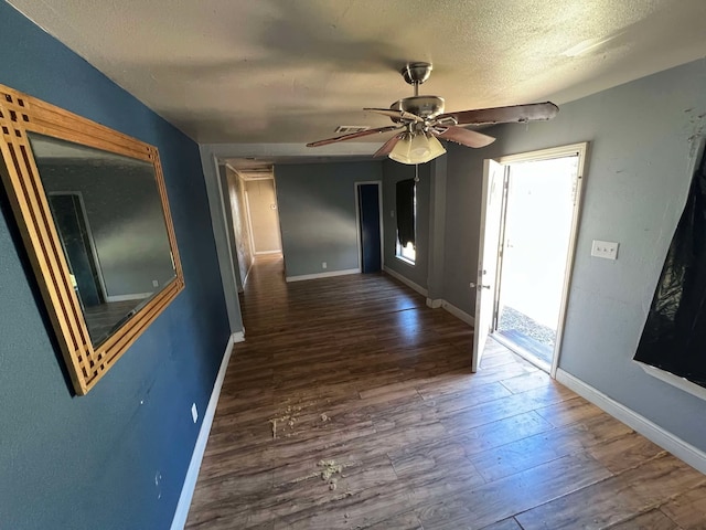 hall with visible vents, a textured ceiling, baseboards, and wood finished floors