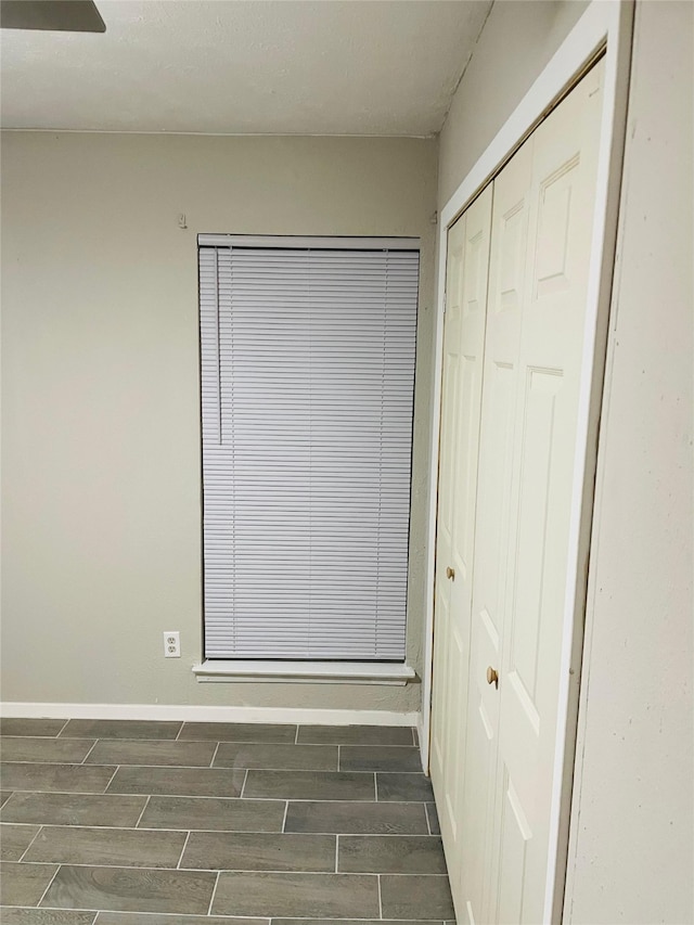 unfurnished bedroom featuring wood finish floors, a closet, and baseboards