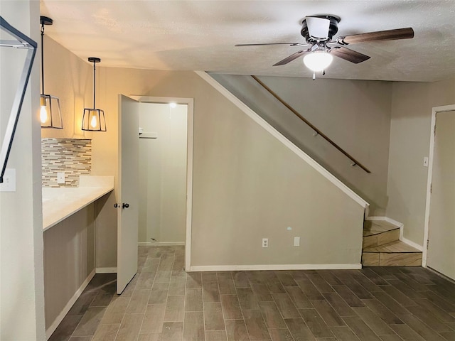 interior space with ceiling fan, a textured ceiling, wood finished floors, and stairs