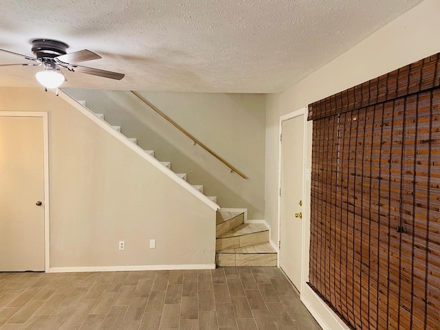 entrance foyer with ceiling fan, stairway, wood finished floors, and a textured ceiling