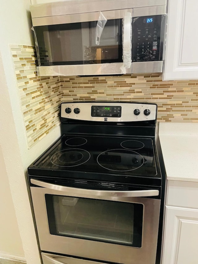 kitchen featuring white cabinetry, light countertops, backsplash, and stainless steel appliances