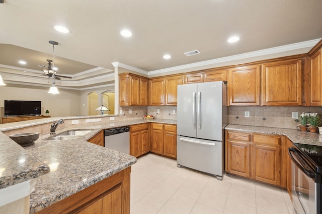 kitchen featuring visible vents, a sink, stainless steel appliances, brown cabinetry, and a raised ceiling