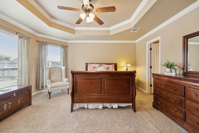 bedroom with a tray ceiling, light colored carpet, visible vents, and ornamental molding