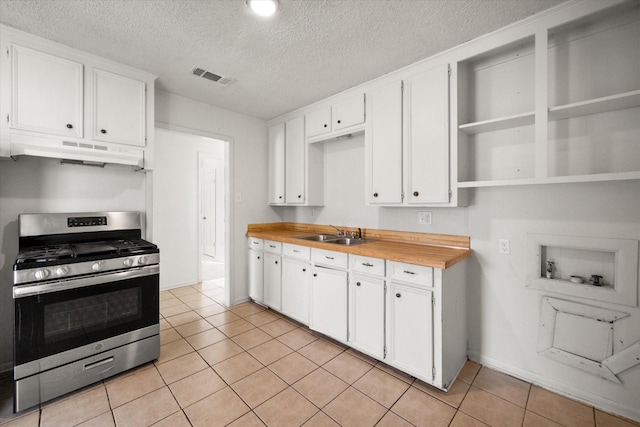 kitchen with stainless steel gas stove, visible vents, white cabinets, under cabinet range hood, and open shelves