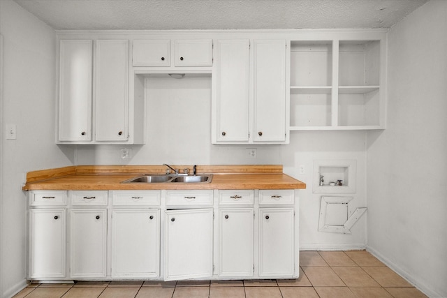 kitchen with light tile patterned floors, a textured ceiling, a sink, white cabinetry, and open shelves