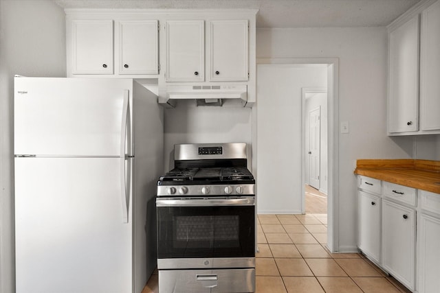 kitchen with freestanding refrigerator, white cabinets, under cabinet range hood, and stainless steel range with gas cooktop