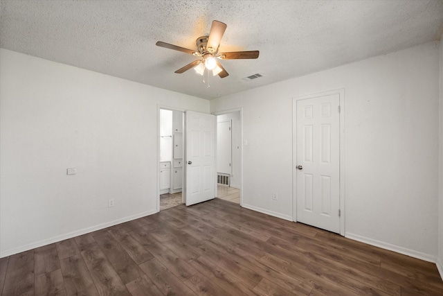 unfurnished bedroom featuring dark wood-style flooring, visible vents, ceiling fan, a textured ceiling, and baseboards