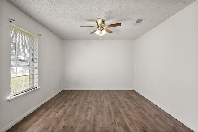 empty room featuring visible vents, a ceiling fan, a textured ceiling, wood finished floors, and baseboards