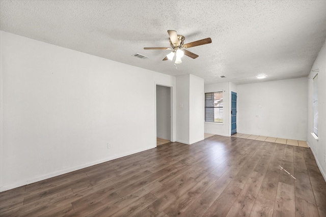 empty room with ceiling fan, a textured ceiling, visible vents, and wood finished floors