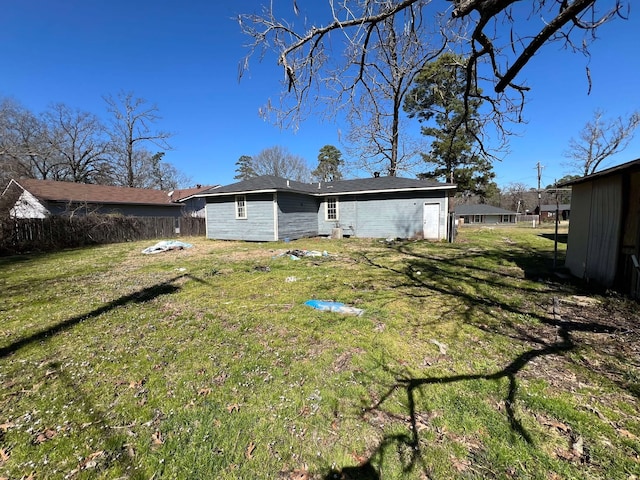 back of house featuring fence and a lawn