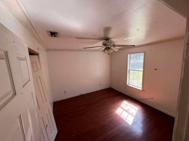 interior space with ceiling fan, visible vents, baseboards, ornamental molding, and dark wood finished floors