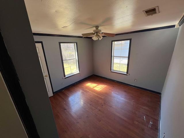 spare room with visible vents, a ceiling fan, ornamental molding, wood finished floors, and baseboards