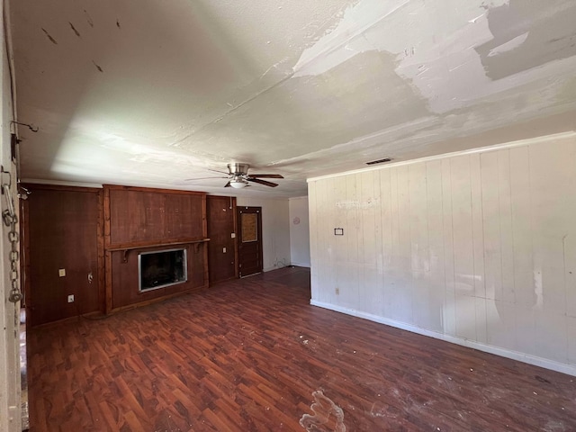 unfurnished living room featuring ceiling fan, visible vents, a fireplace, and wood finished floors