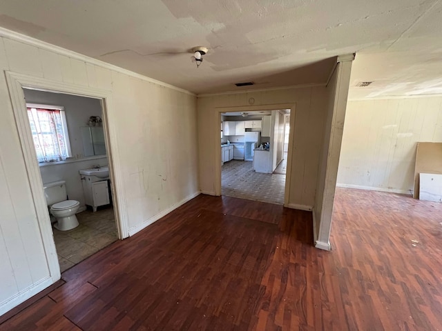 spare room with baseboards, visible vents, dark wood-style floors, crown molding, and a sink