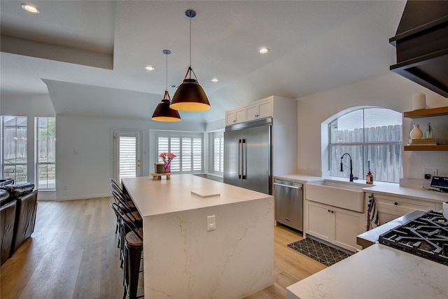 kitchen with a center island, stainless steel appliances, light wood-style floors, open shelves, and a sink