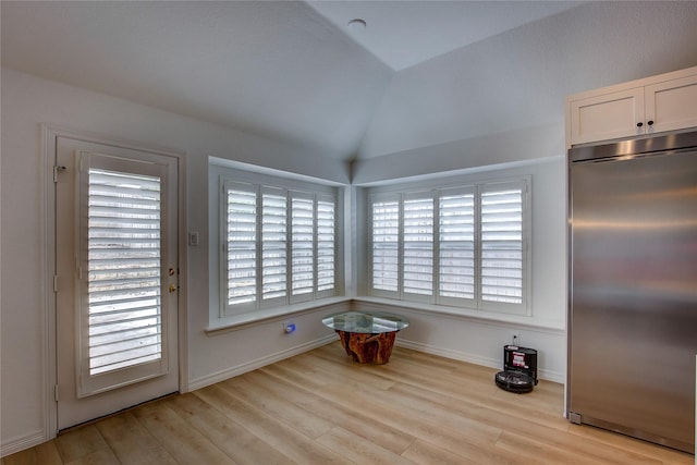 interior space with vaulted ceiling, wood finished floors, and baseboards