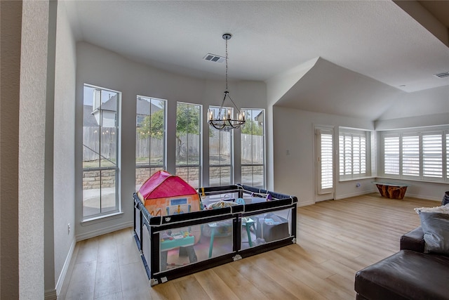 rec room with a chandelier, wood finished floors, visible vents, and baseboards