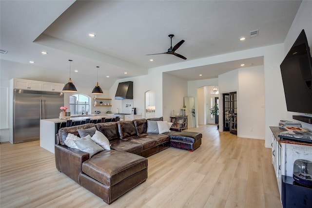 living room with light wood-style floors, ceiling fan, arched walkways, visible vents, and recessed lighting