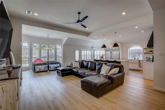 living area with light wood-style floors, ceiling fan with notable chandelier, visible vents, and recessed lighting