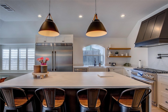 kitchen featuring light countertops, visible vents, a sink, premium range hood, and appliances with stainless steel finishes