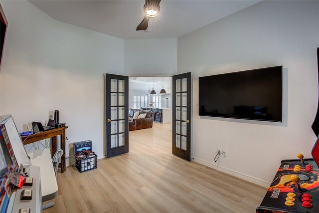 interior space featuring baseboards, french doors, wood finished floors, and a high ceiling