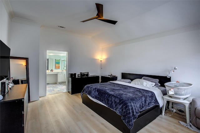 bedroom featuring lofted ceiling, visible vents, ornamental molding, ensuite bath, and light wood-type flooring