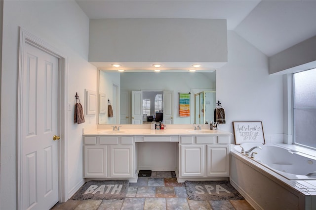 bathroom featuring vaulted ceiling, a sink, a jetted tub, and double vanity