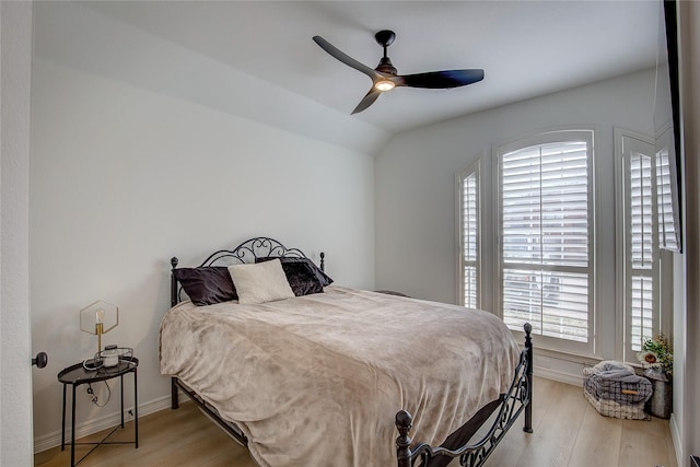 bedroom featuring light wood-style floors, vaulted ceiling, ceiling fan, and multiple windows