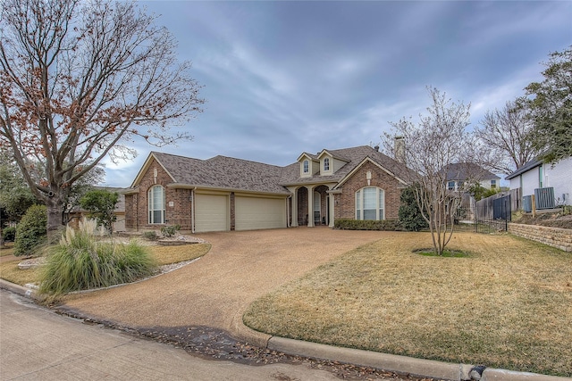 view of front of house with brick siding, an attached garage, a front lawn, and fence