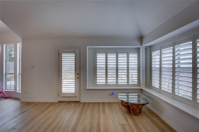 unfurnished dining area with lofted ceiling, baseboards, and wood finished floors