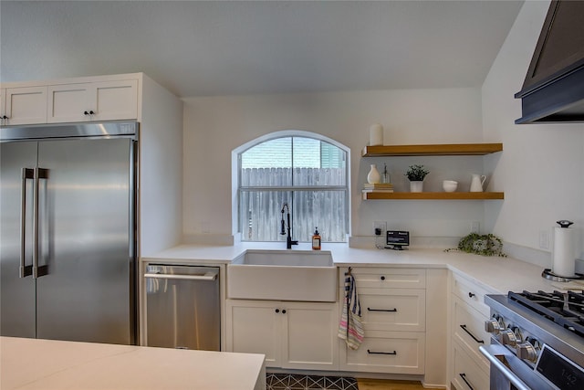 kitchen featuring white cabinets, light countertops, a sink, and high quality appliances