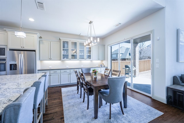 dining area with baseboards, visible vents, dark wood finished floors, and a chandelier