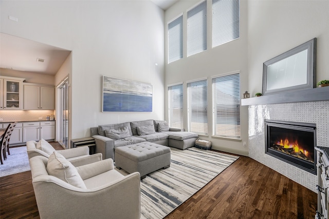 living area with a wealth of natural light, dark wood-style flooring, a fireplace, and baseboards