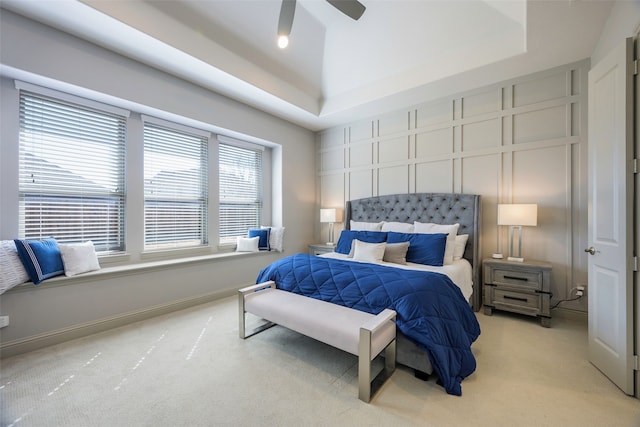 bedroom featuring baseboards, a tray ceiling, ceiling fan, and light colored carpet