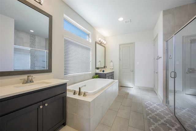 full bathroom featuring a garden tub, two vanities, visible vents, a stall shower, and a sink