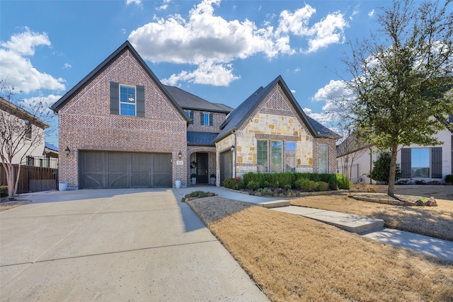 view of front of house featuring a garage, brick siding, fence, driveway, and stone siding